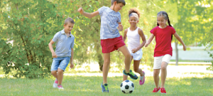 image of four kids playing soccer in a yard.