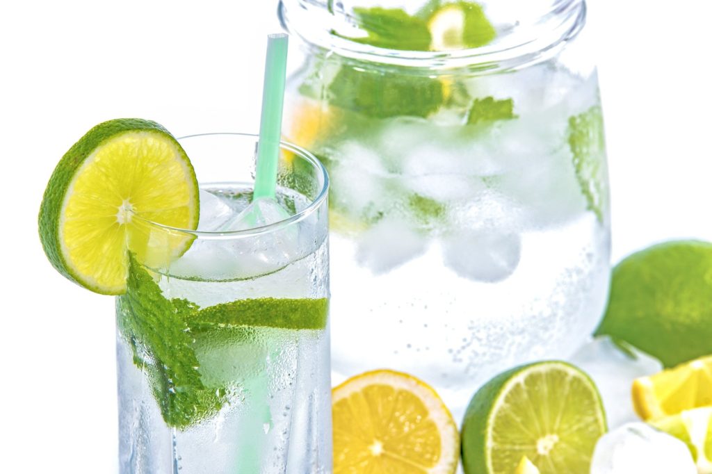 pitcher and glass of water with lemon and lime slices