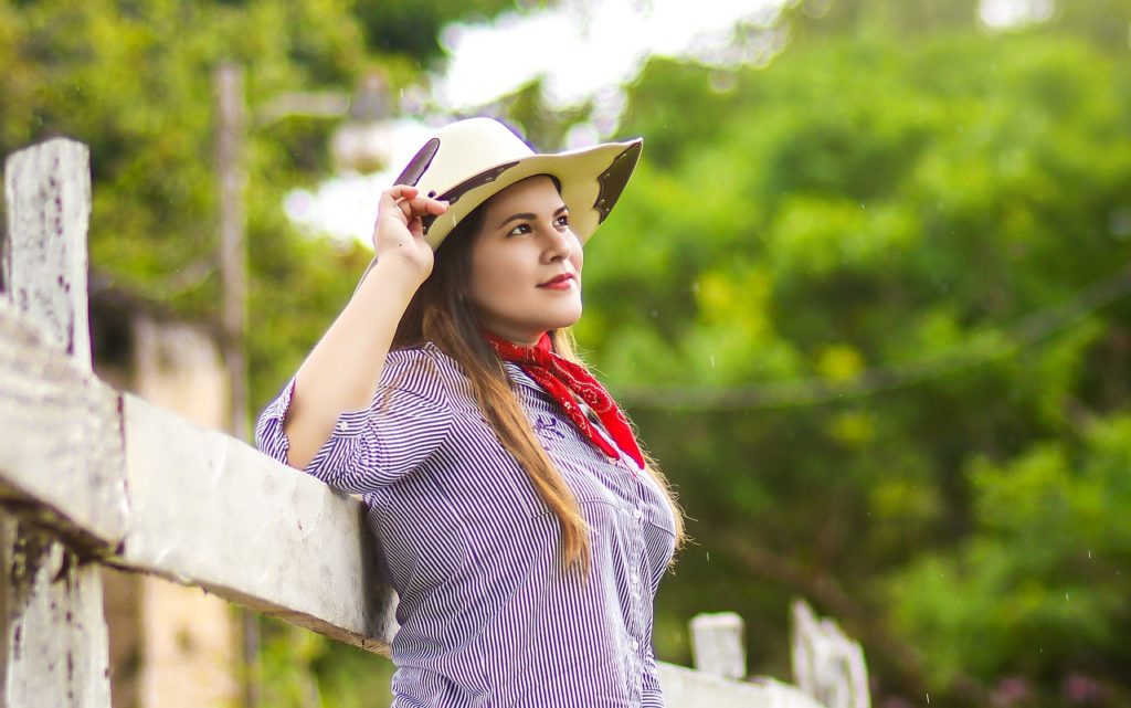 woman farmer leaning back against a split rail fence